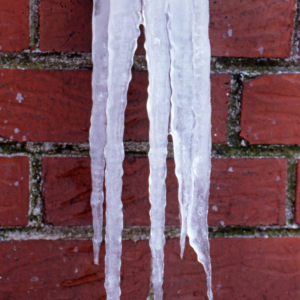 a close up view of brickwork with long, thick icicles hanging in front of it